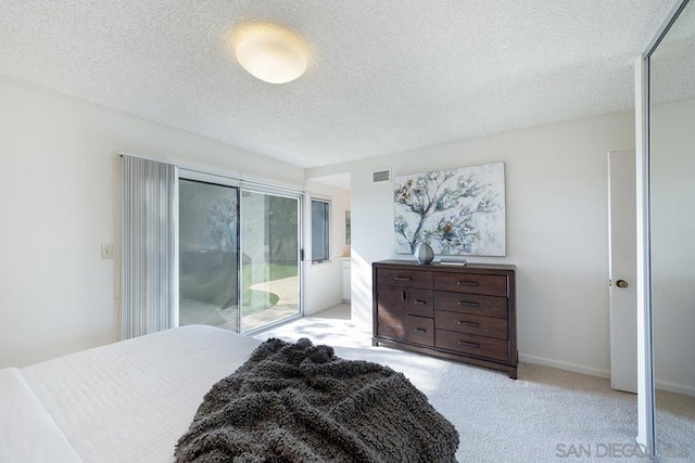 bedroom with access to exterior, light colored carpet, and a textured ceiling