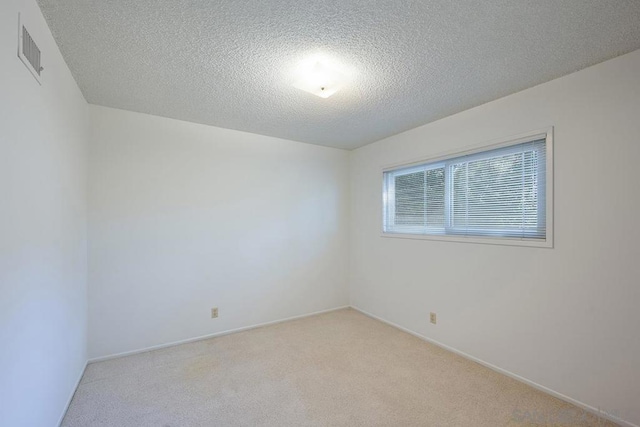 carpeted empty room featuring a textured ceiling