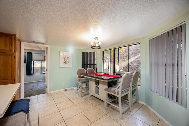 tiled dining area featuring a textured ceiling and a notable chandelier