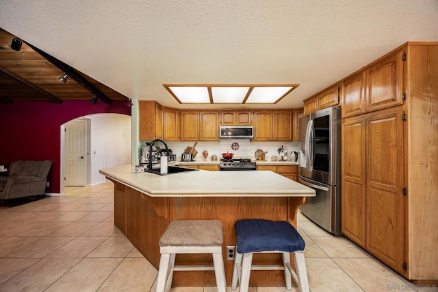 kitchen featuring light tile patterned flooring, sink, a kitchen bar, kitchen peninsula, and stainless steel appliances