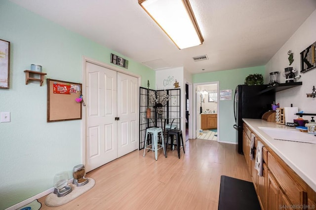 kitchen featuring black fridge, sink, and light hardwood / wood-style flooring