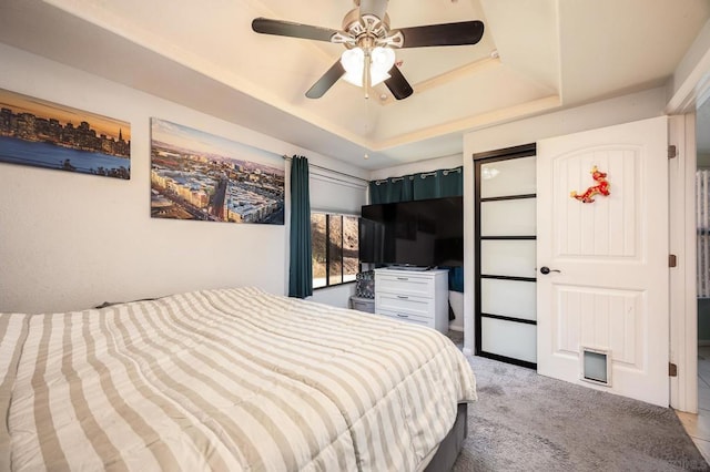 carpeted bedroom featuring ceiling fan and a raised ceiling