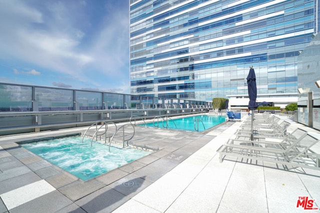 view of swimming pool with a hot tub and a patio area