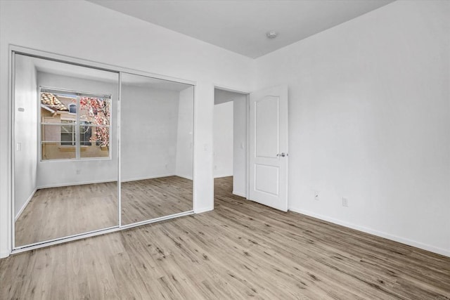 unfurnished bedroom with light wood-type flooring and a closet