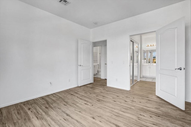 unfurnished bedroom with connected bathroom and light hardwood / wood-style flooring