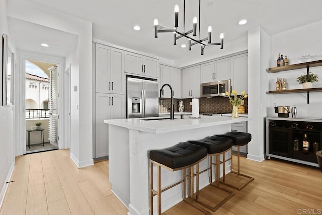 kitchen featuring wine cooler, light hardwood / wood-style floors, an island with sink, and appliances with stainless steel finishes