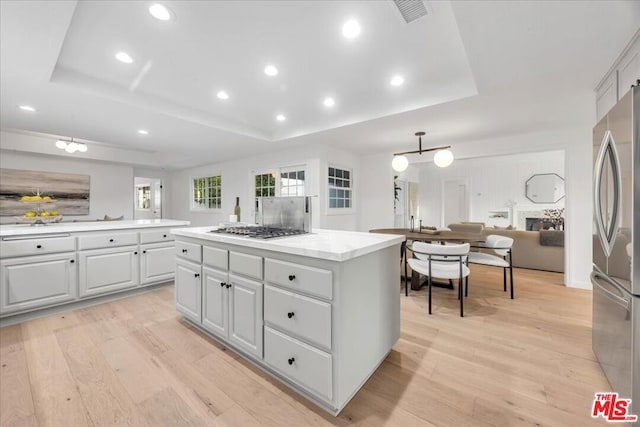 kitchen featuring appliances with stainless steel finishes, a raised ceiling, and a kitchen island