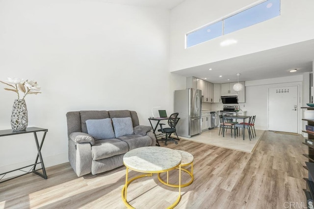 living room with light hardwood / wood-style flooring and a high ceiling