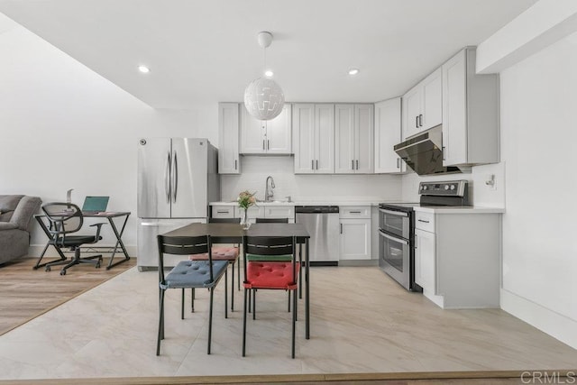 kitchen with sink, appliances with stainless steel finishes, white cabinets, decorative backsplash, and decorative light fixtures