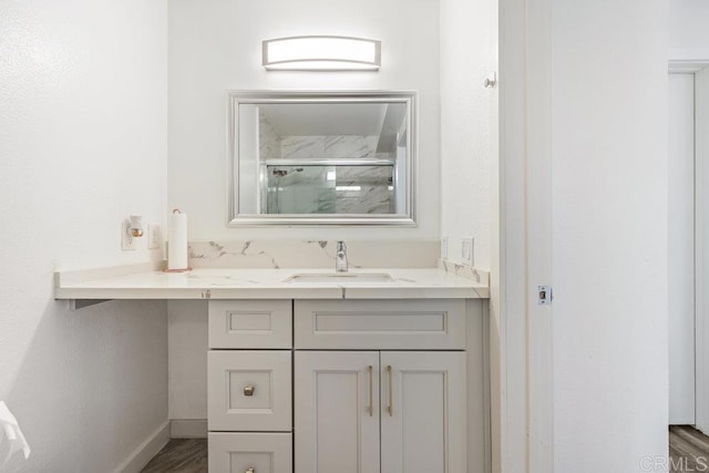 bathroom with vanity, a shower with shower door, and wood-type flooring