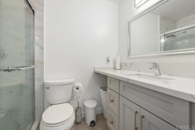 bathroom with a shower with door, vanity, tile patterned floors, and toilet