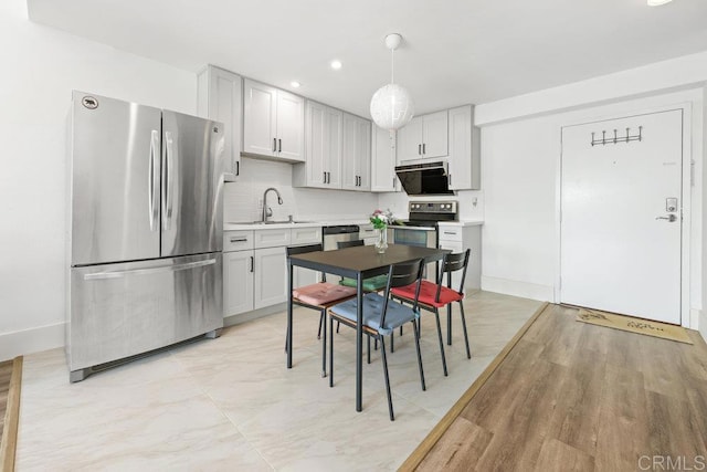 kitchen featuring pendant lighting, sink, backsplash, stainless steel appliances, and range hood