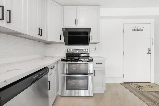 kitchen with light stone countertops, backsplash, stainless steel appliances, and white cabinets