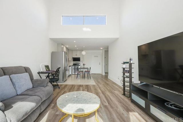 living room with a towering ceiling and light wood-type flooring