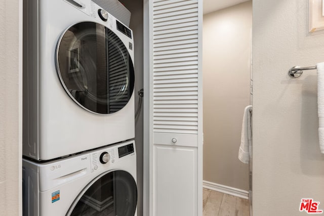 clothes washing area featuring light hardwood / wood-style floors and stacked washer / dryer