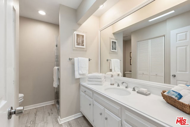 bathroom with vanity, toilet, a shower with shower door, and hardwood / wood-style floors