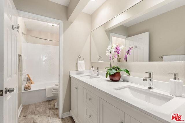 full bathroom featuring wood-type flooring, shower / washtub combination, vanity, and toilet