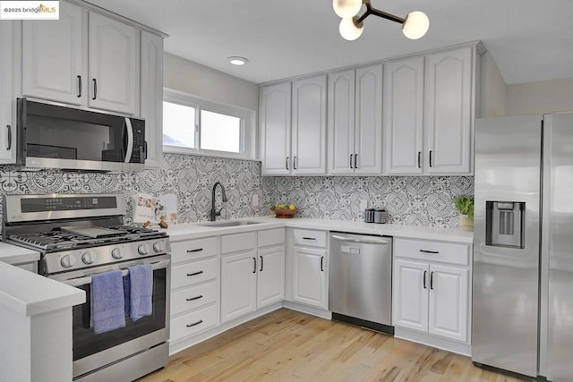 kitchen with sink, white cabinetry, tasteful backsplash, stainless steel appliances, and light hardwood / wood-style floors