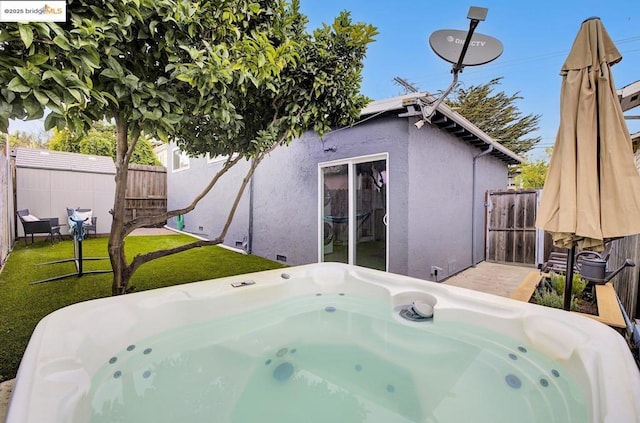 rear view of house with a lawn and a hot tub