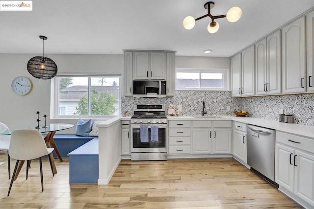 kitchen with sink, appliances with stainless steel finishes, hanging light fixtures, tasteful backsplash, and breakfast area