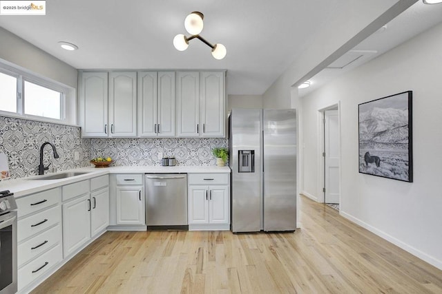 kitchen featuring appliances with stainless steel finishes, sink, decorative backsplash, and light wood-type flooring