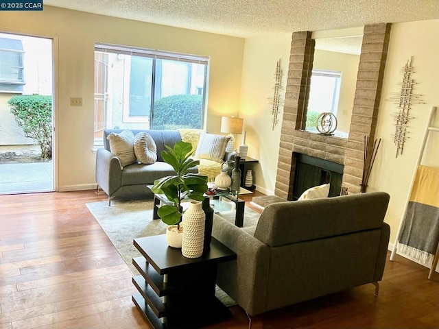 living room featuring hardwood / wood-style flooring, a brick fireplace, and a textured ceiling