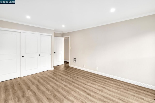 unfurnished bedroom featuring ornamental molding, a closet, and light wood-type flooring