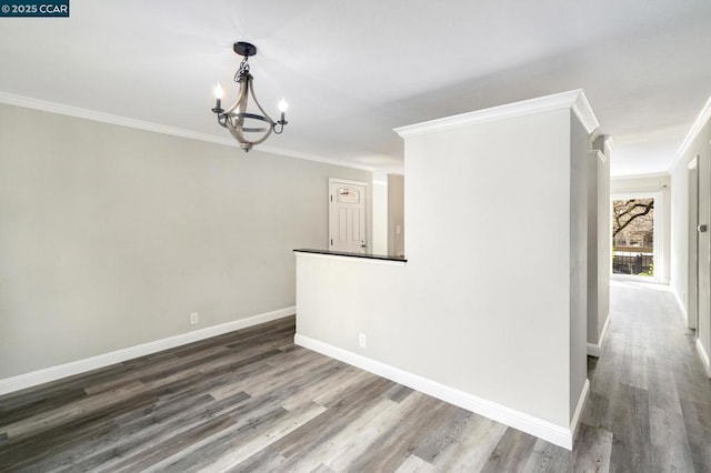 unfurnished room featuring wood-type flooring, crown molding, and an inviting chandelier