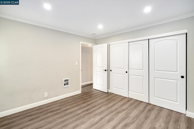 unfurnished bedroom with crown molding, wood-type flooring, and a closet