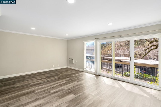 empty room featuring ornamental molding, wood-type flooring, and a wall unit AC