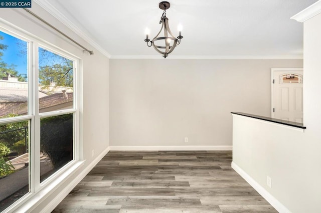 unfurnished dining area with crown molding, wood-type flooring, and a notable chandelier