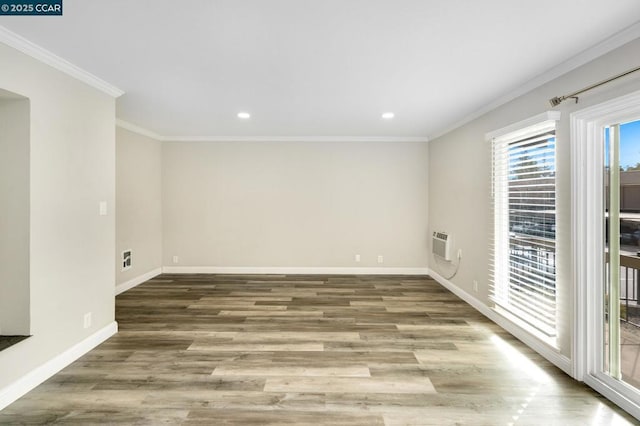 unfurnished room featuring ornamental molding, a wall mounted AC, and light wood-type flooring