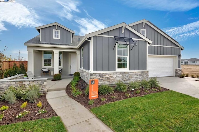 view of front of home featuring a garage, covered porch, and a front lawn