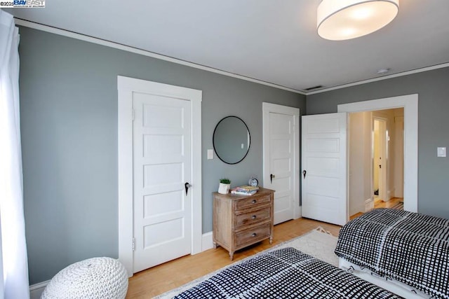 bedroom with ornamental molding and light hardwood / wood-style floors