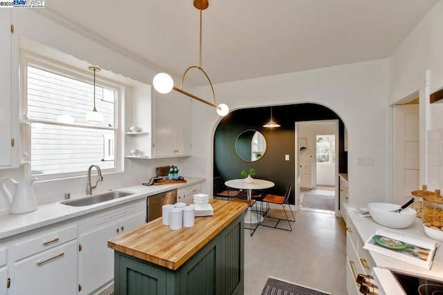 kitchen with butcher block countertops, sink, hanging light fixtures, a center island, and white cabinets