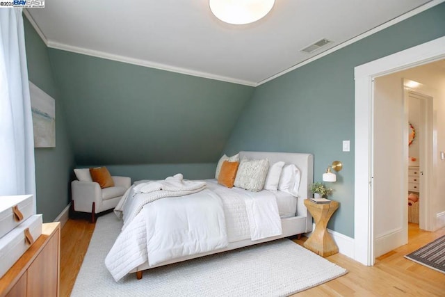 bedroom featuring lofted ceiling, crown molding, and light hardwood / wood-style flooring