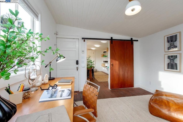 interior space featuring dark hardwood / wood-style flooring, vaulted ceiling, wooden ceiling, and a barn door