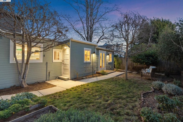 property exterior at dusk featuring a yard