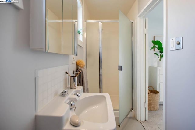 bathroom with sink, decorative backsplash, and a shower with shower door