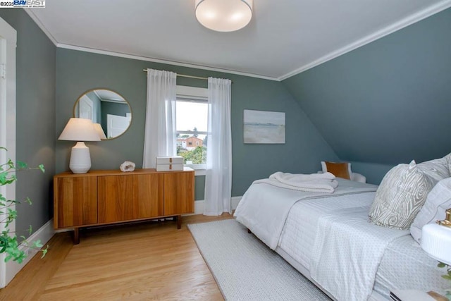 bedroom with crown molding, vaulted ceiling, and light wood-type flooring