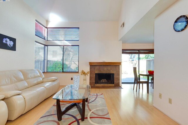 living room with a fireplace, a high ceiling, and light wood-type flooring