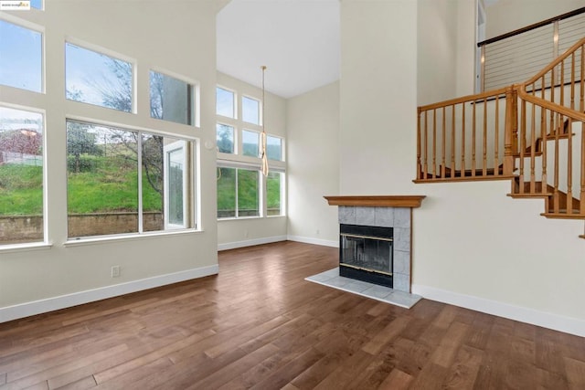 unfurnished living room featuring hardwood / wood-style flooring, a fireplace, and a towering ceiling