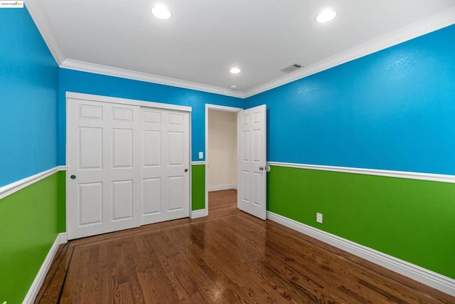 unfurnished bedroom featuring hardwood / wood-style flooring, ornamental molding, and a closet