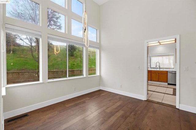 unfurnished bedroom with dark hardwood / wood-style flooring, sink, a towering ceiling, and connected bathroom