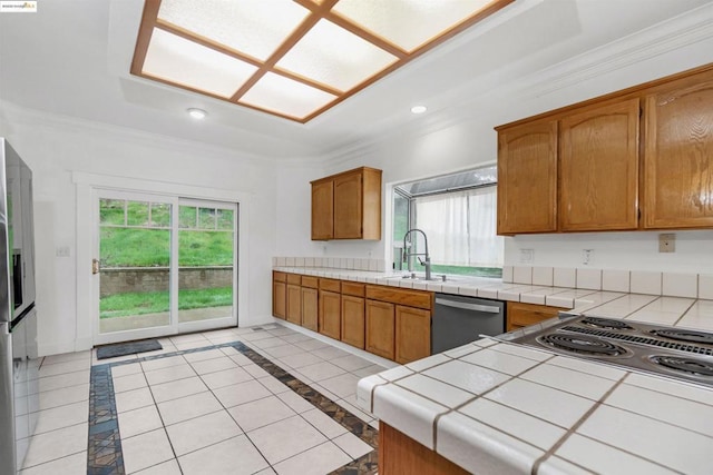 kitchen with sink, tile countertops, ornamental molding, and appliances with stainless steel finishes