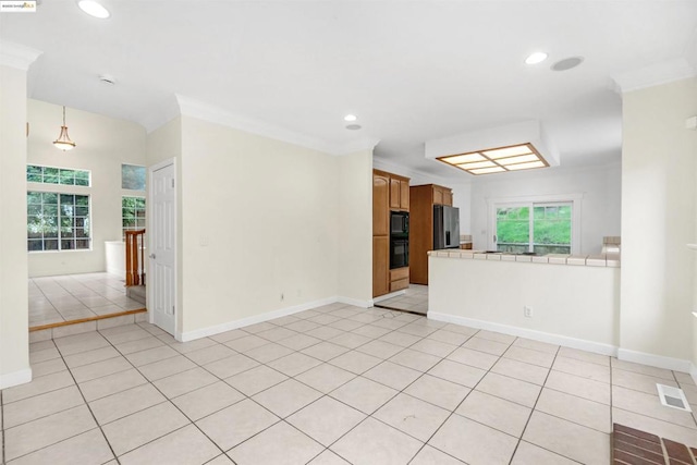 empty room with ornamental molding, plenty of natural light, and light tile patterned floors