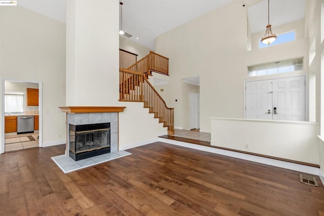 unfurnished living room with hardwood / wood-style floors, a tile fireplace, and a high ceiling