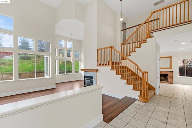 stairway featuring a tiled fireplace, hardwood / wood-style flooring, and a high ceiling