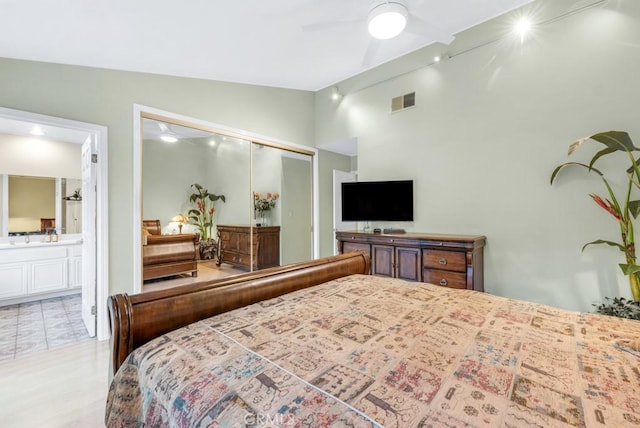 bedroom featuring lofted ceiling, ensuite bath, a closet, and ceiling fan