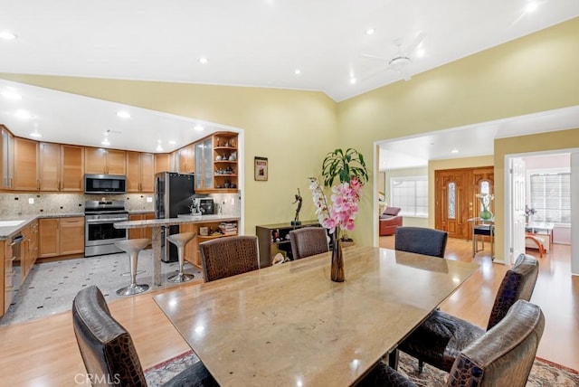 dining room with ceiling fan, lofted ceiling, and light wood-type flooring